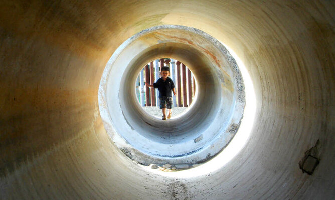 Ein Kind läuft durch einen kleinen Tunnel. 