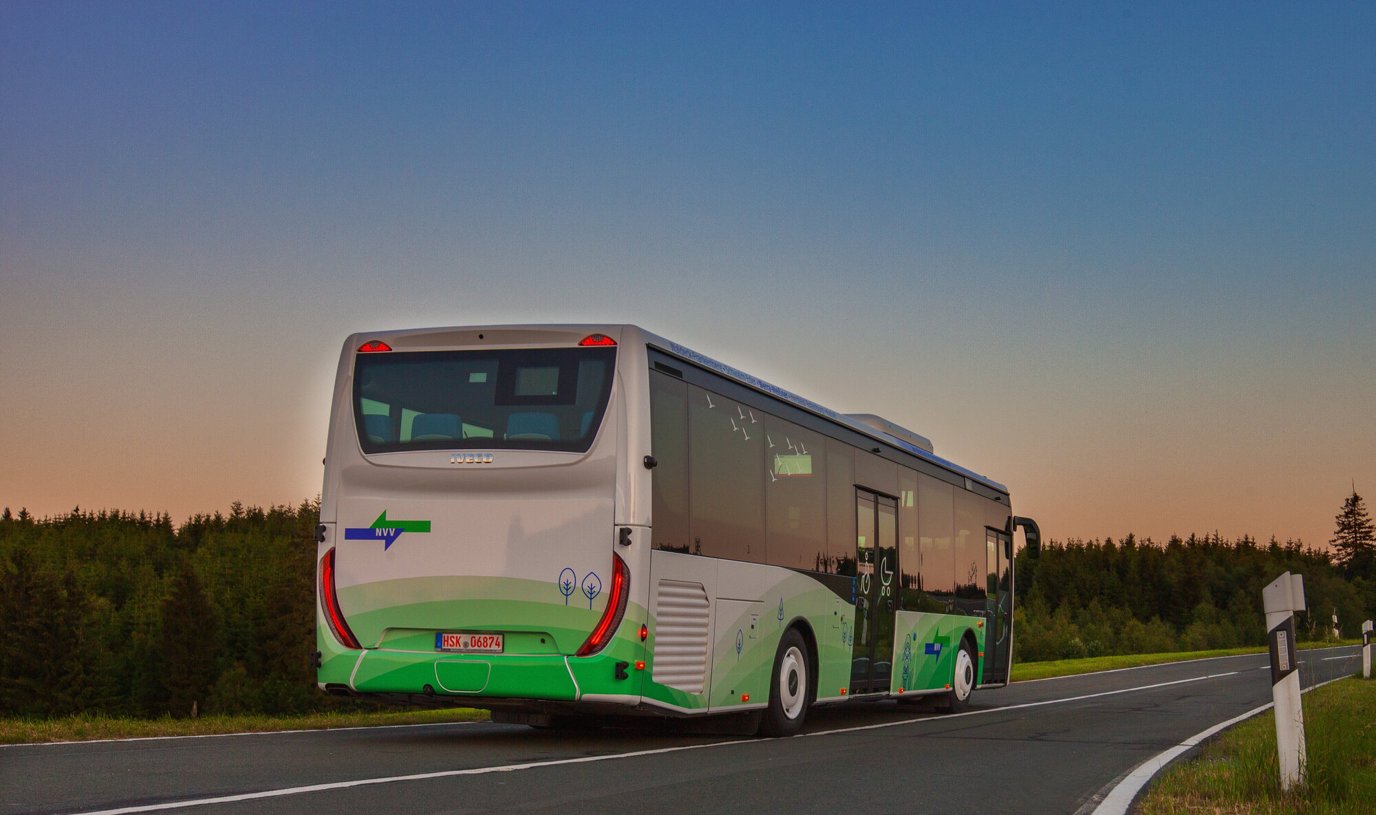 Ein Bus fährt bei Dämmerung auf einer Landstraße