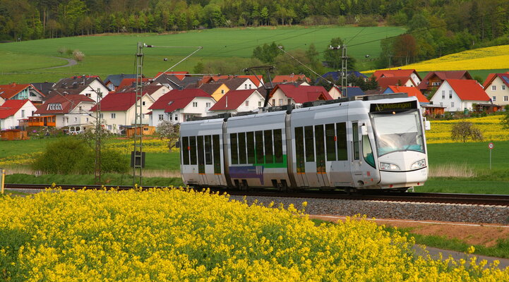 Eine Tram fährt zwischen Rapsfeldern
