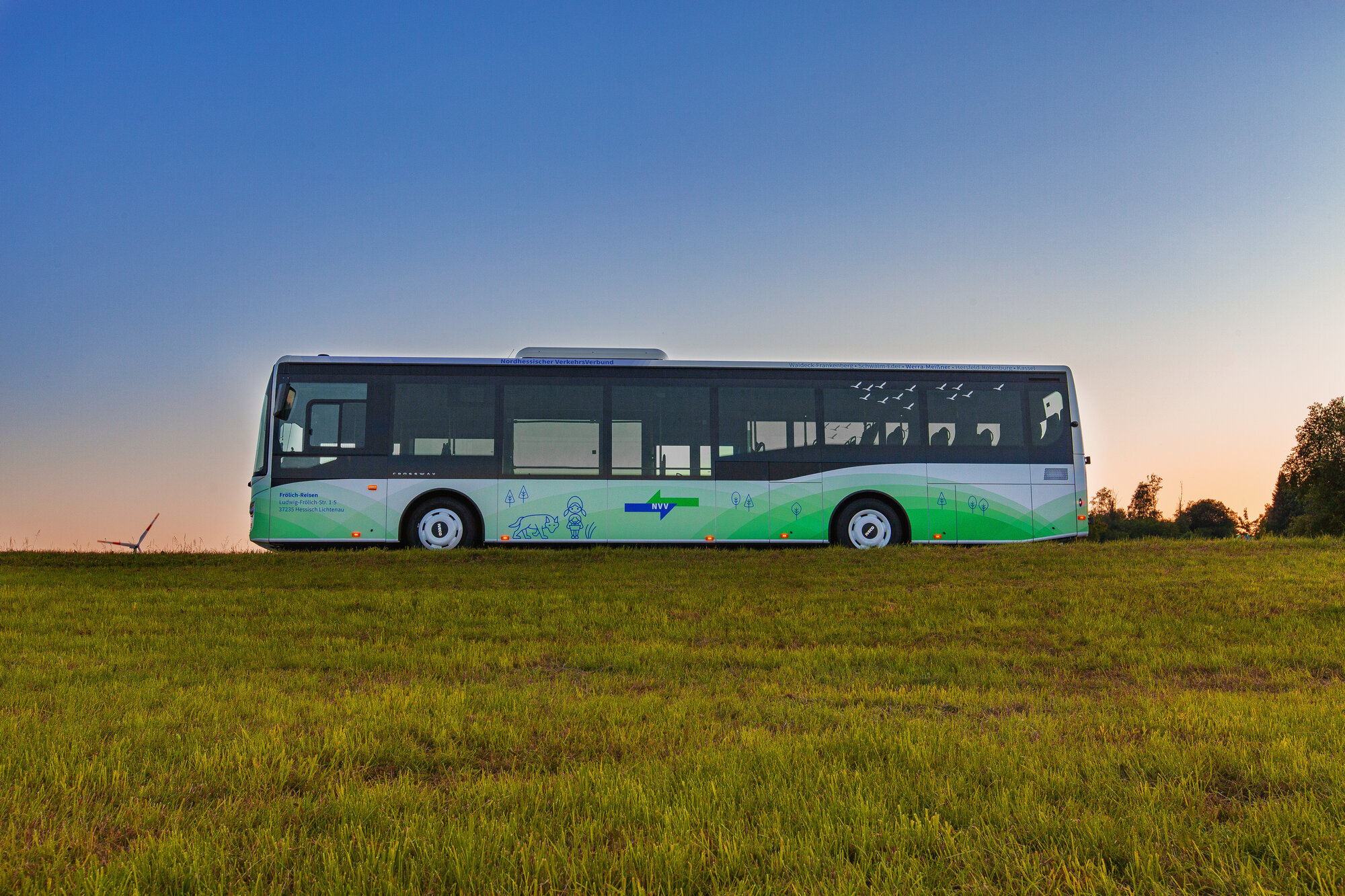 Ein Bus fährt bei Dämmerung auf einer Landstraße.