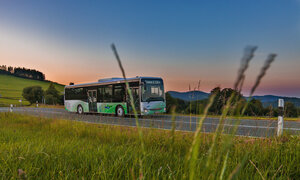 Ein grün weißer NVV Bus mit Märchendesign fährt bei Dämmerung eine Landstraße entlang