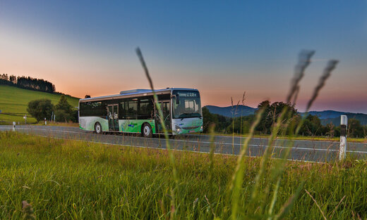 Ein grün weißer NVV Bus mit Märchendesign fährt bei Dämmerung eine Landstraße entlang