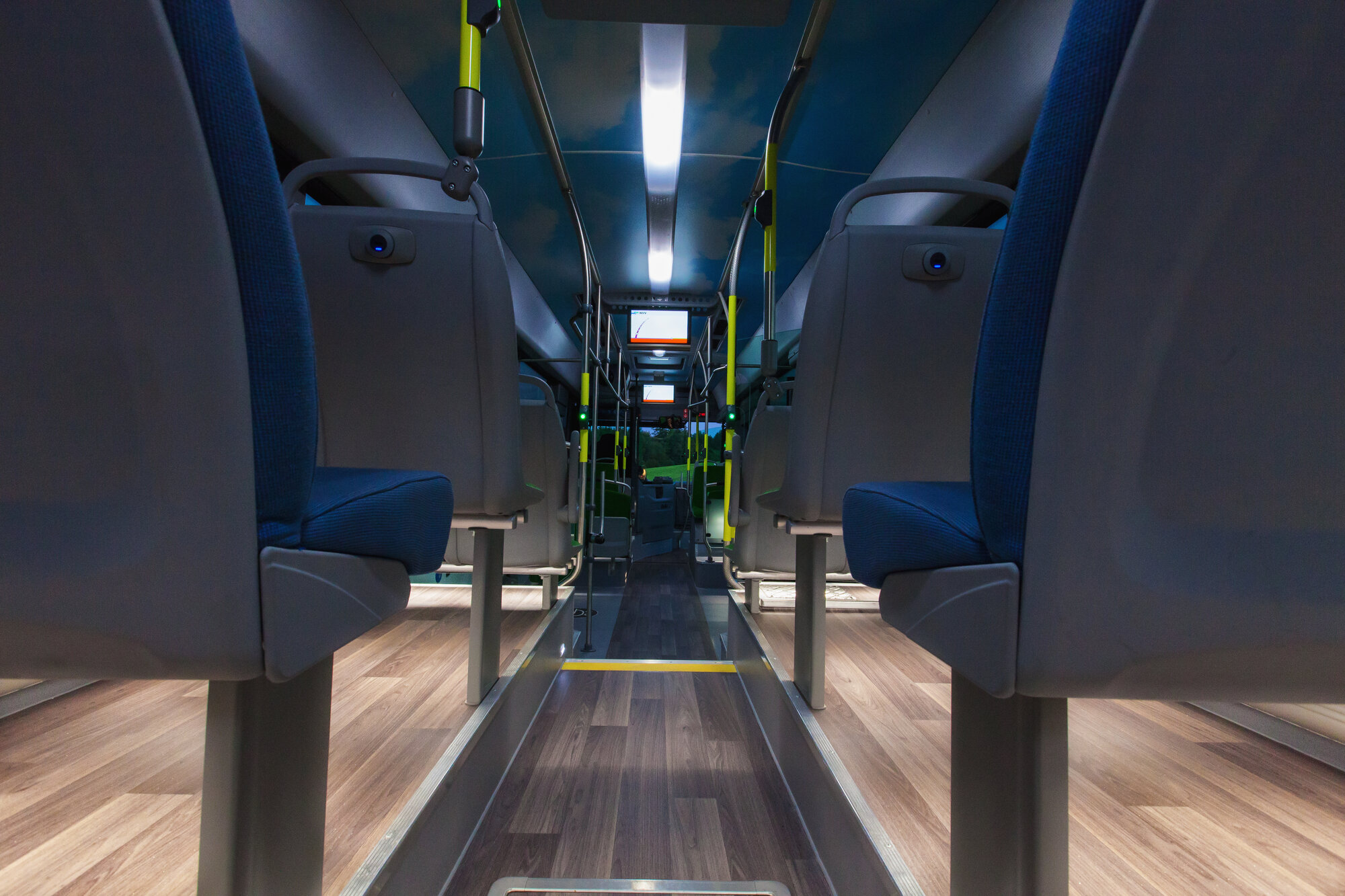 Innenansicht eines Busses von hinten nach vorne mit Beleuchtung der Sitzreihen. 