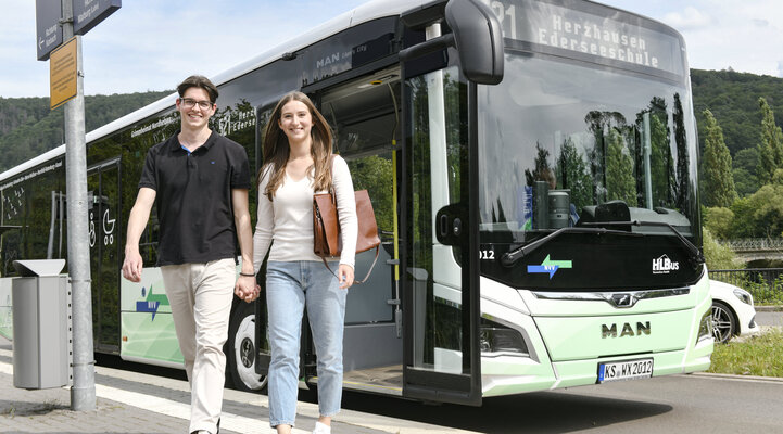 Ein Pärchen siegt an einer Haltestelle aus einem Bus aus. 