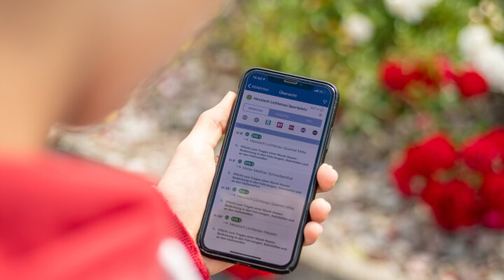 Ein junger Mann schaut über sein Smartphone mit der NVV-App nach Verbindungen