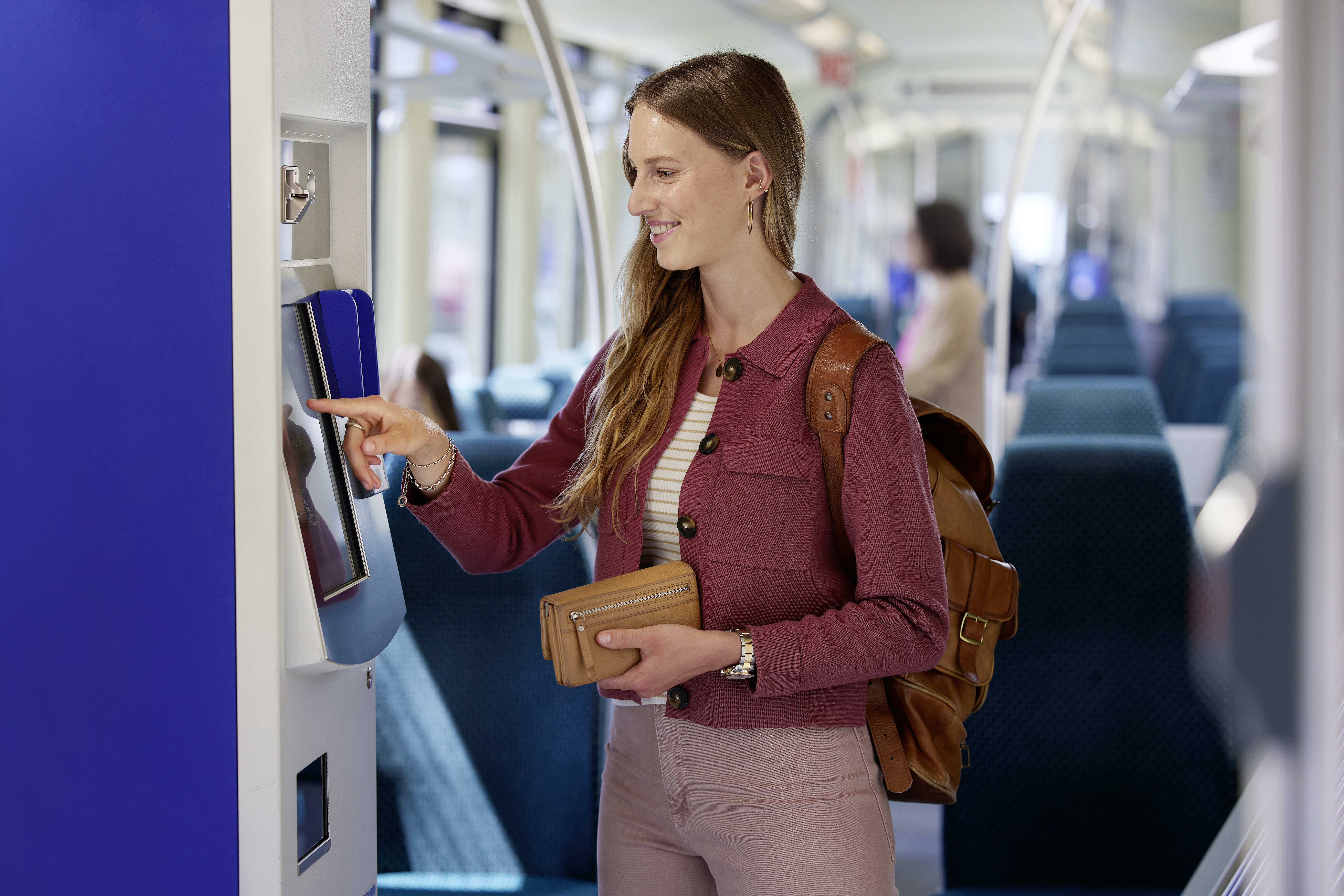 Eine Frau die in einer Tram ein Ticket am Ticketautomaten kauft.